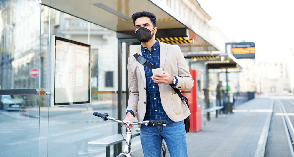 Business man commuter with smartphone on the way to work outdoors in city, coronavirus concept.